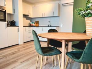 a dining room table with green chairs and a kitchen at Abbey Green Lodge in Breda