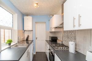 cocina con fregadero y fogones horno superior en Fantastic 3 Bedroom House *Free Parking*, en Wolverhampton
