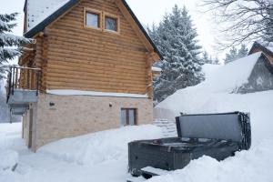 ein Blockhaus mit einem Whirlpool im Schnee in der Unterkunft Drvena Kuca RUŽA in Kopaonik