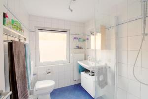 Baño blanco con aseo y lavamanos en Toms Gästehaus en Schleiden