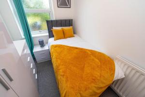 um quarto com uma cama com lençóis amarelos e uma janela em Fantastic 3 Bedroom House *Free Parking* em Wolverhampton