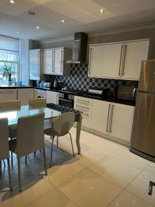 Una cocina con gabinetes blancos y una mesa y sillas. en WEST END -Stunning, 2 bedroom, main door flat with private parking, en Glasgow