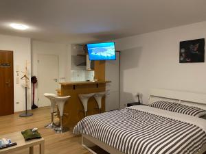 - une chambre avec un lit et une télévision murale dans l'établissement studio CHEZ TONY, à Luxembourg