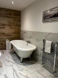 a white bath tub in a bathroom with marble tiles at WEST END -Stunning, 2 bedroom, main door flat with private parking in Glasgow