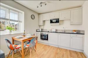 a kitchen with white cabinets and a table and chairs at Miltons Holiday Let in Grimston