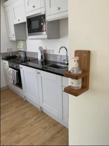 a white kitchen with a sink and a stove at Miltons Holiday Let in Grimston