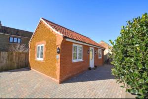 a brick house with a white door on a brick driveway at Miltons Holiday Let in Grimston