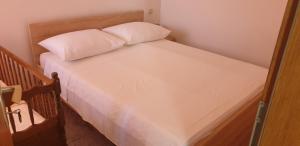 a bed with white sheets and a pillow on it at Apartments PHARIA in Jelsa