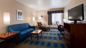 ランチョ・クカモンガにあるBest Western Plus Heritage Inn Ontario Rancho Cucamongaの青いソファ、薄型テレビが備わるホテルルームです。