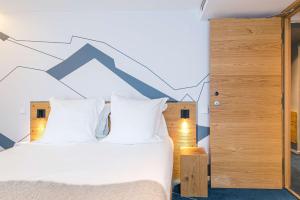 a bedroom with a bed with white sheets and a geometric wall at Best Western Chalet les Saytels in Le Grand-Bornand
