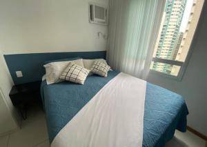 a bedroom with a blue and white bed and a window at ITAPARICA BEACH 24HRS in Vila Velha