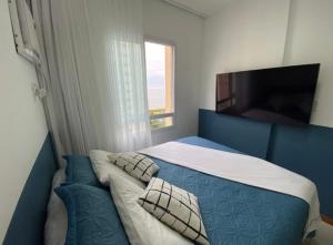 a bedroom with a blue bed with pillows and a tv at ITAPARICA BEACH 24HRS in Vila Velha +32 photos