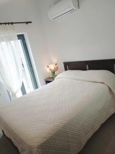 a bedroom with a white bed and a window at Vina's Stone House in Limeni