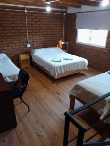 a bedroom with two beds and a brick wall at Duplex Chacabuco in San Fernando del Valle de Catamarca