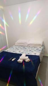 1 cama con 2 toallas y 2 controles remotos en Lindo Flat no Residencial Maraca Beach, en Porto de Galinhas