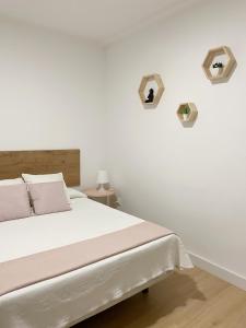 a bedroom with a bed with white walls and two shelves at Hostal Sol in Zamora