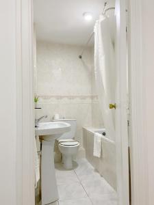 a white bathroom with a toilet and a sink at Hostal Sol in Zamora