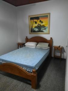 - un lit dans une chambre avec une photo sur le mur dans l'établissement Chácara Charbella, à Três Ranchos