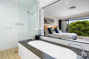 a bathroom with a bath tub and a bedroom at Pullman Magenta Shores Resort in The Entrance
