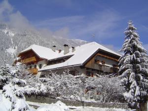 ein schneebedecktes Gebäude mit einem Weihnachtsbaum in der Unterkunft Residence Pichlerhof in Oberrasen