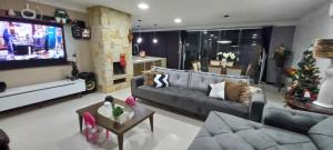 sala de estar con sofá y TV en Casa confortável com piscina en Tramandaí
