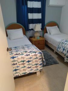 a room with two beds and a table with a lamp at Luna 39 in Oranjestad