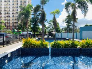a swimming pool with palm trees and a building at Quayside Condo near Airport in Mactan