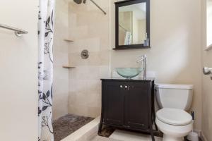 a bathroom with a toilet and a sink and a mirror at Comfortable Home, 7 min Walk to Beach, Hot Tub, in Pompano Beach