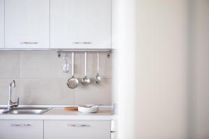 a kitchen with white cabinets and a sink and utensils at Casa con ampio terrazzo, vista lago e giardino in Toscolano Maderno