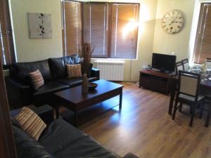 sala de estar con sofá, mesa y reloj en Comfort Private Apartments, en Bansko