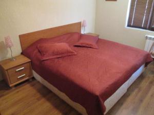 a bed with a red comforter and two pillows at Comfort Private Apartments in Bansko