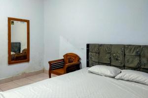 a bedroom with a bed and a mirror and a chair at Fauziah Hotel Syariah Kendari in Pipulu