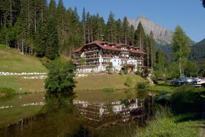 una casa grande en una colina junto a un lago en Hotel Plank, en San Martino di Castrozza