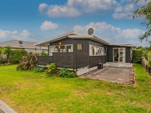 una casa con una casa negra con un patio en Bach Life on Seabreeze - Whangamata Holiday Home, en Whangamata
