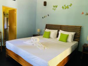 a bedroom with a large bed with green and white pillows at Sigiri Siesta Homestay in Sigiriya