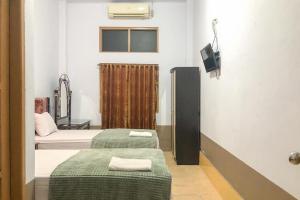 a small room with two beds and a television at RedDoorz Syariah At Hotel Baruga Bonerate Selayar in Benteng