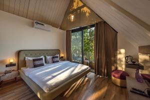 um quarto com uma cama grande e uma janela grande em SaffronStays Hillside Harriers, Lonavala - A Frame chalets with bathtub for couples em Lonavala