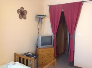 a bedroom with a tv and a door with red curtains at Penzion Duna in Komárno