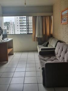 uma sala de estar com um sofá, uma secretária e uma janela em Flat Amplo em Boa Viagem em Recife mais 12 fotografias