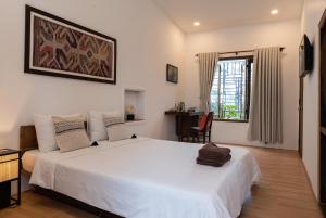 1 dormitorio con 1 cama blanca grande y escritorio en The Bohome, en Quy Nhon