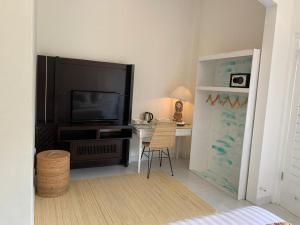 a living room with a television and a desk with a chair at NIKINIKO Beach House by Lolavillas - 100mts to the beach in Canggu