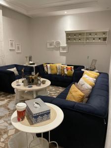 سمو1 في الرياض: غرفة معيشة مع أريكة زرقاء وطاولتين