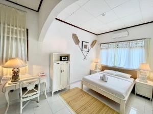 a white bedroom with a bed and a desk at NIKINIKO Beach House by Lolavillas - 100mts to the beach in Canggu