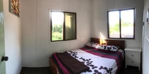 sypialnia z łóżkiem i 2 oknami w obiekcie Noungan Farm Homestay w mieście Penampang