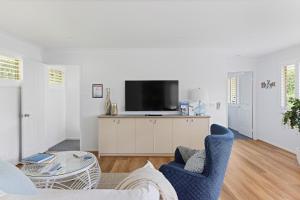 uma sala de estar com uma televisão e duas cadeiras e uma mesa em HideAway on Tallean em Nelson Bay