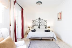 a white bedroom with a large white bed with red curtains at 138 ALCALA Perfect Stay by Sunkeyrents in Alcalá