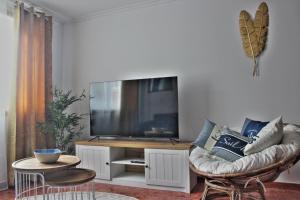 ein Wohnzimmer mit einem Sofa und einem Flachbild-TV in der Unterkunft Malpica Greek Home in Malpica