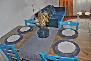 einem Esstisch mit weißen Tellern und einem blauen Sofa in der Unterkunft Malpica Greek Home in Malpica