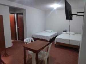 Cette chambre comprend 2 lits, une table et une télévision. dans l'établissement Amenli Lodging House, à Piura