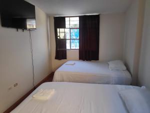 a small room with two beds and a window at Amenli Lodging House in Piura